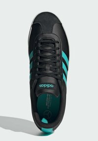 Sort sneakers med turkise accenter og tre striber. Har en snørebåndsdesign, struktureret overdel og gummisål. Mærker synlige.