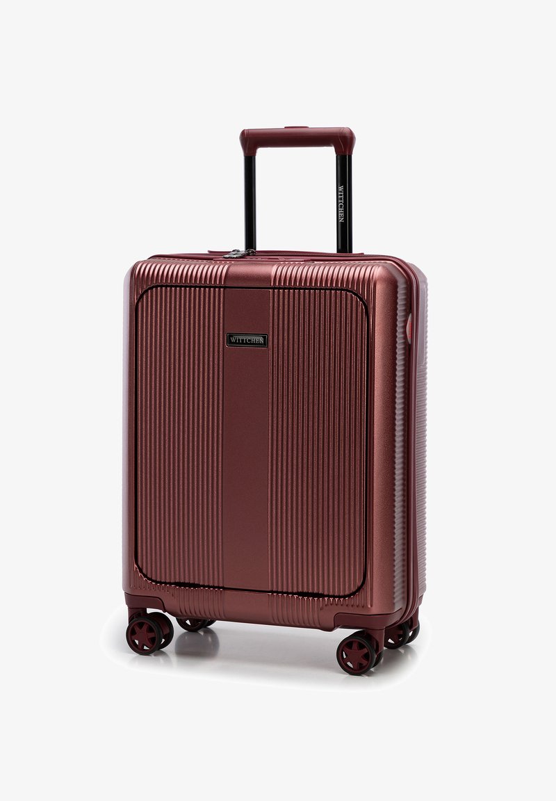 Valigia rigida con finitura burgundy metallica. Presenta una texture a strisce verticali, manico retrattile e quattro ruote nere per la mobilità.
