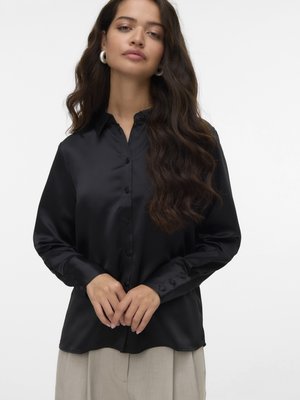 Black satin blouse with a buttoned front, pointed collar, and long sleeves featuring rounded cuffs. Smooth texture and relaxed fit.