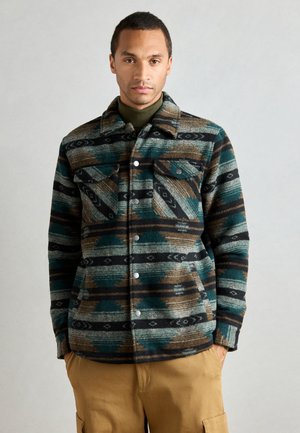 Chaqueta de camisa de lana con un patrón multicolor en teal, marrón y negro, con dos bolsillos en el pecho y cierre de botones a presión.