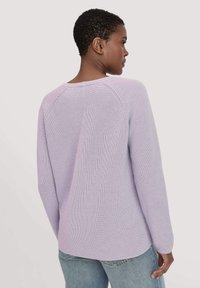 Lila gebreide trui met een ontspannen pasvorm, geribbelde textuur en raglanmouwen. Heeft een ronde halslijn en een iets langere achterkant.