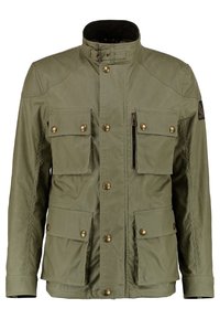 Olivově zelená bunda vyrobená z odolné tkaniny, s vysokým límcem, několika předními kapsami, mosaznými odnímatelnými knoflíky a kapsou na zip.