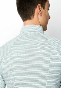 Herrenhemd mit einem kleinen, geometrischen Muster in Teal und Weiß. Verfügt über einen klassischen Kragen und eine glatte Stoffstruktur.