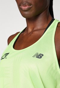 Světlý zelený sportovní tank top s perforovanou texturou, zdobený černým logem na hrudi a kontrastním černým popruhem.