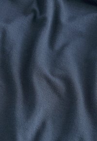 Marinblått tyg med en mjuk textur och subtilt ribbat mönster, som har mjuka veck och draperingar och reflekterar ljus i olika nyanser.