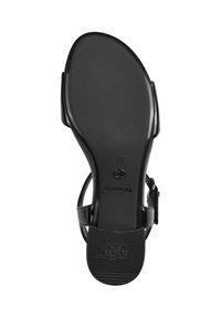 Sandalia de charol negro con correa para el tobillo ajustable, tacón curvado y suela de goma texturizada con detalles de marca.