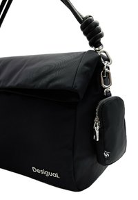 Sac à épaule noir en matériau durable, avec un rabat pliable, une poche zippée, une texture lisse et des accents en métal argenté.