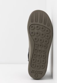 Czarna podeszwa buta z teksturowaną powierzchnią, na której znajdują si�ę okrągłe wzory i otwory wentylacyjne, oznaczona numerem "38" oraz logo "Camper".