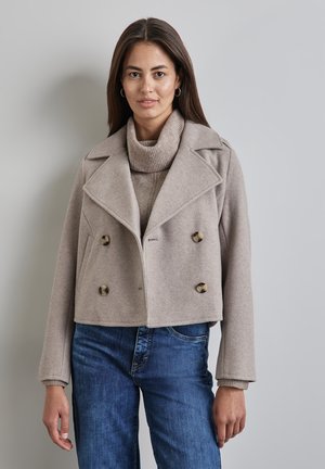 Beige cropped double-breasted wool blend jacket with large buttons, sharp lapels, and structured shoulders, paired with a knitted cream turtleneck.