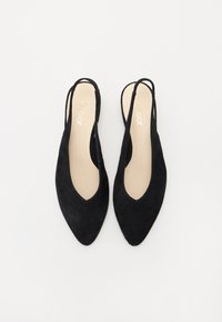 Chaussures slingback en suède noir avec un bout pointu et des côtés ouverts. La semelle intérieure est de couleur claire, avec une subtile marque visible.