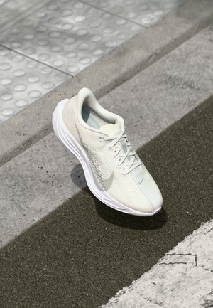 Kevyt juoksukenkä off-white-värissä, jossa on teksturoitu verkkopintainen yläosa, vahvistettu kanta ja joustava pohja. Nike-logo sivussa.