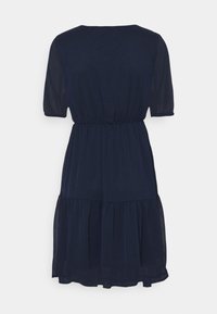 Tummansininen polvipituinen mekko, jossa on lyhyet hihat, elastinen vyötärö ja kerroksittain leikkautuva hame vaalealla taustalla.