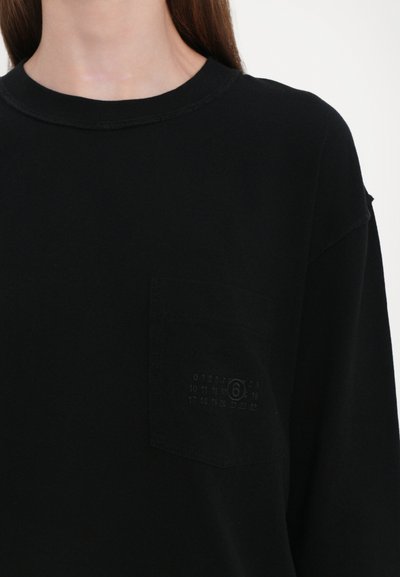 Svart långärmad t-shirt i bomull, med en framficka som har en subtil tonad kalendergrafik. Kanten är något fransad.