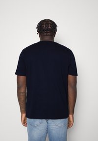 Granatowa bawełniana koszulka z krótkim rękawem, okrągłym dekoltem i luźnym krojem. Posiada gładką fakturę oraz prosty design bez widocznych logo czy wzorów.