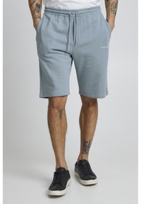 Shorts en coton bleu clair avec une taille élastique et un cordon de serrage. Poches latérales et logo imprimé sur le bas à l'avant.
