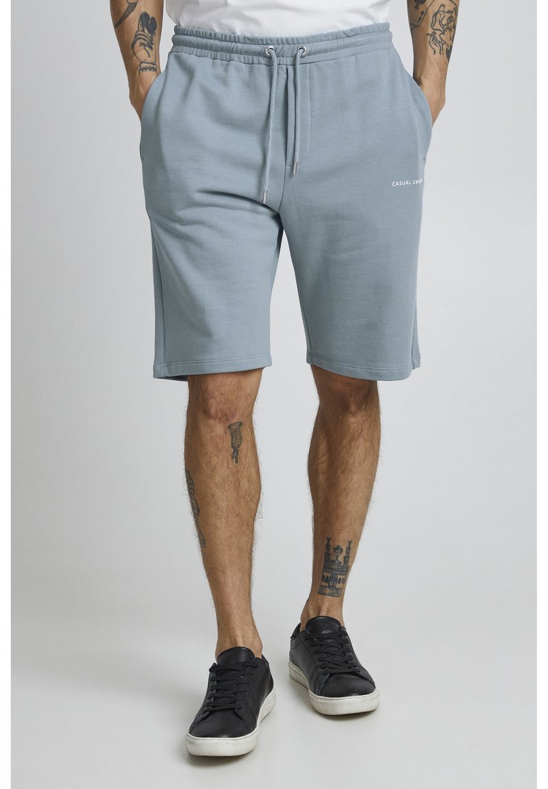 Shorts en coton bleu clair avec une taille élastique et un cordon de serrage. Poches latérales et logo imprimé sur le bas à l'avant.