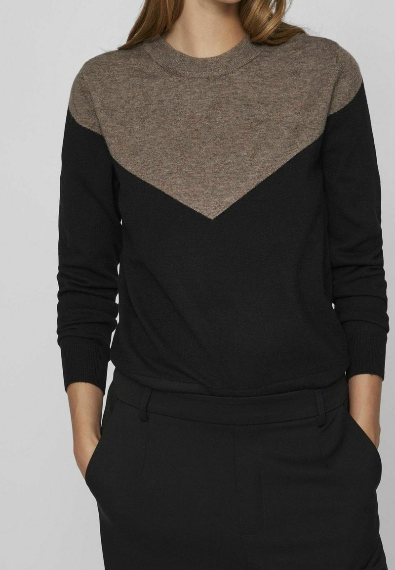 Maglione nero con collo rotondo e maniche lunghe. La parte superiore presenta un motivo triangolare marrone. Realizzato in un tessuto morbido e strutturato.