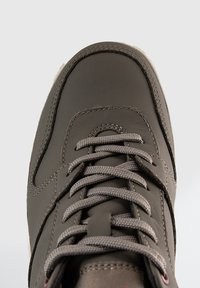 Bruna lädersneakers med texturerad yta, som har grå snören och förstärkt sömnad. Rund tå och subtila detaljer på sidorna.