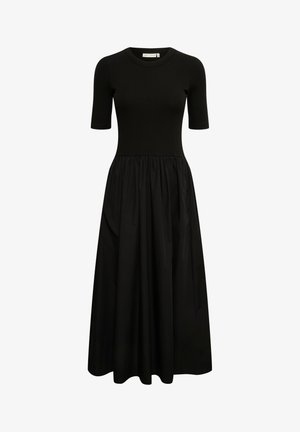 Črna obleka s prilegajočim se rebrastim zgornjim delom in prosto padajočo, zbrano krilom. Kratki rokavi, okrogla izreza in mehak material brez vidnih vzorcev.