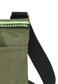 Grön tygväska med en svart dragkedja och limegröna detaljer. Inkluderar en svart rem och en texturerad yta. Kompakt design.