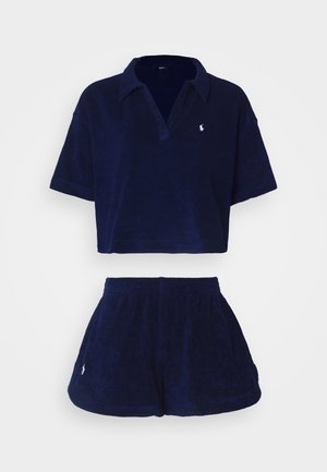 Navy blue terry cloth loungewear set featuring a cropped polo shirt with a collar and matching shorts, both with small logo accents.