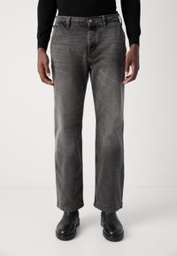 Grijze denim jeans met een rechte pasvorm, vijf zakken, subtiele vervaagde textuur en contrasterende stiksels, gecombineerd met zwarte laarzen.