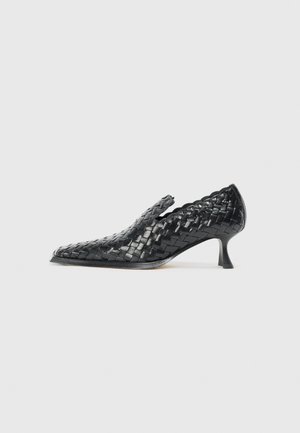 Scarpa in pelle intrecciata nera con punta affilata e tacco basso. Presenta dettagli incisi lungo i lati e una texture liscia e lucida.