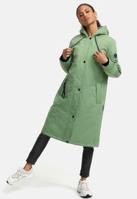 Long green parka jacket with a hood, featuring a lightweight texture, snap buttons, side pockets, and a slightly glossy finish.