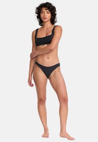 Ensemble de bikini noir comprenant un top à encolure carrée avec des bretelles larges et un bas taille basse, fabriqué en tissu lisse et extensible. Pas de motifs notables.