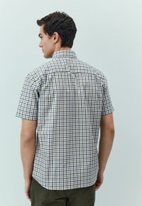 Camicia a maniche corte a quadri con motivo navy, bianco e tan, con colletto standard e vestibilità rilassata.