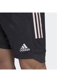 Czarne sportowe szorty z różowym wzorem w trzy paski po boku. Posiadają białe logo Adidas oraz lekką, gładką fakturę materiału.