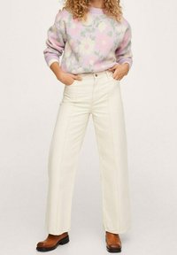 Pull en maille aux couleurs pastel et motif floral, associé à un pantalon crème taille haute à jambes larges et des bottines marron à talons.