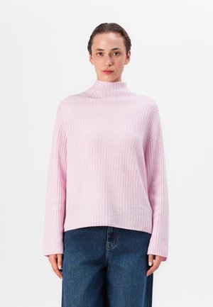 Lyserosa ribbet turtleneck genser med lange ermer og en avslappet passform, kombinert med mørkeblå vide jeans.