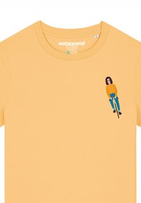 Geel T-shirt met korte mouwen en een ronde hals, met daarop een cartoonfiguur met een bril die op een fiets rijdt aan de linkerkant.