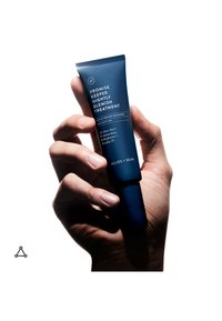 Hand holding a blue tube of Promise Keeper Nightly Blemish Treatment by Allies of Skin with visible product text and clear background.