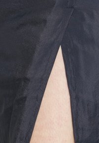 Tecido azul-marinho com uma textura suave, apresentando uma fenda lateral e detalhes de costura limpos. Design minimalista com um brilho subtil.