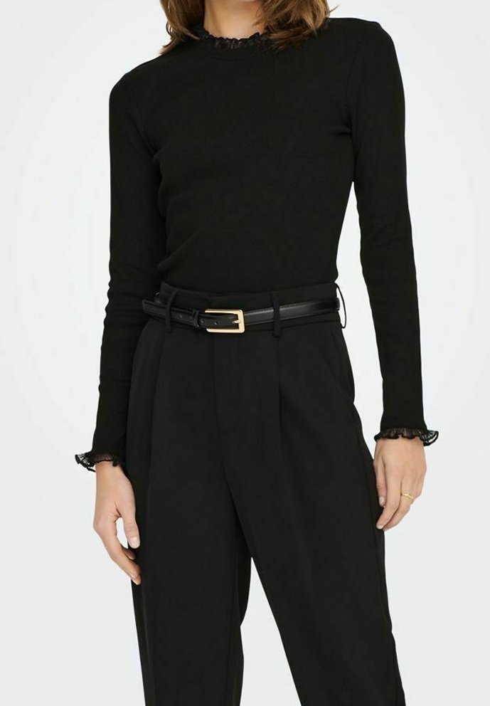 Svart långärmad topp med rynkad halsringning, kombinerad med högmidjade svarta byxor och ett svart bälte med detalj av ett guldspänne.