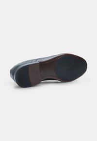 Scarpa di pelle mostrata dal fondo, con una parte anteriore e un tallone in nero testurizzato e una sezione centrale marrone su uno sfondo bianco.