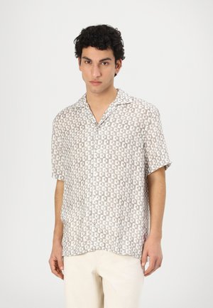Camisa de manga corta, abotonada, en color beige claro con un patrón geométrico. Elaborada en tejido ligero, cuenta con cuello de campamento y un corte relajado.