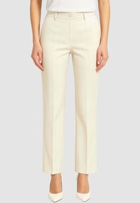 Pantaloni su misura color crema con righe verticali, chiusura con bottone e taglio dritto. Tessuto liscio e vita aderente.