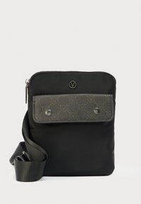 Majhna črna torbica čez ramo z nastavljivim trakom, siva sprednja preklopna z vzorcem in kovinskimi gumbi na pritrditev ter z zgornjo zadrgo.