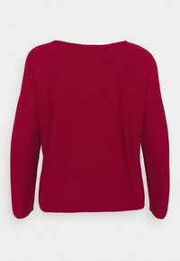 Pull rouge à manches longues avec un large col, coupe décontractée, texture côtelée et fentes sur les côtés, en tissu doux. Vue arrière montrée.