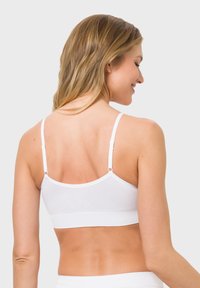 Weißes Baumwoll-Bralette mit dünnen Trägern, nahtlosem Design und strukturiertem Bund. Verfügt über verstellbare Trägerbefestigungen auf der Rückseite.