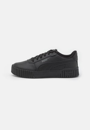 Zapatilla deportiva Puma negra de corte bajo con suela texturizada, cierre de cordones en la parte delantera y logotipo de Puma en el lateral y el talón, con fondo blanco liso.