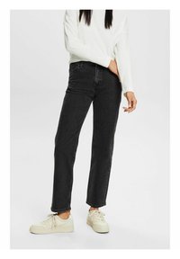 Czarne dżinsy o prostym kroju, z pięcioma kieszeniami i wysokim stanem. Połączone z białą bluzką i off-white trampkami.