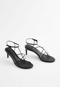 Svarta läder högklackade sandaler med tunna korslagda remmar, en slank design, öppen tå och ankelremmar för säker passform.