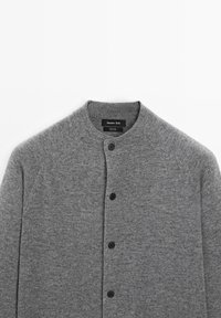 Grauer Cardigan aus weichem Strickstoff mit hohem Kragen, fünf schwarzen Knöpfen und glatter Textur sowie Raglansäulen.