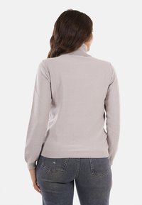Maglione grigio chiaro con collo alto, maniche lunghe e orlo a coste aderente. Presenta sottili dettagli luccicanti su una morbida texture.