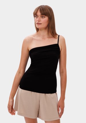 Zwarte een-schoudertop van gladde stof, met een gedrapeerd ontwerp en een verstelbare band, gecombineerd met beige high-waisted shorts.