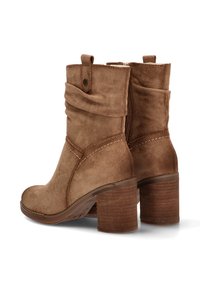 Botas de tobillo de ante marrón con un puño doblado, cremallera lateral y un tacón de madera grueso. Cuenta con detalles de costura y un diseño de punta redondeada.
